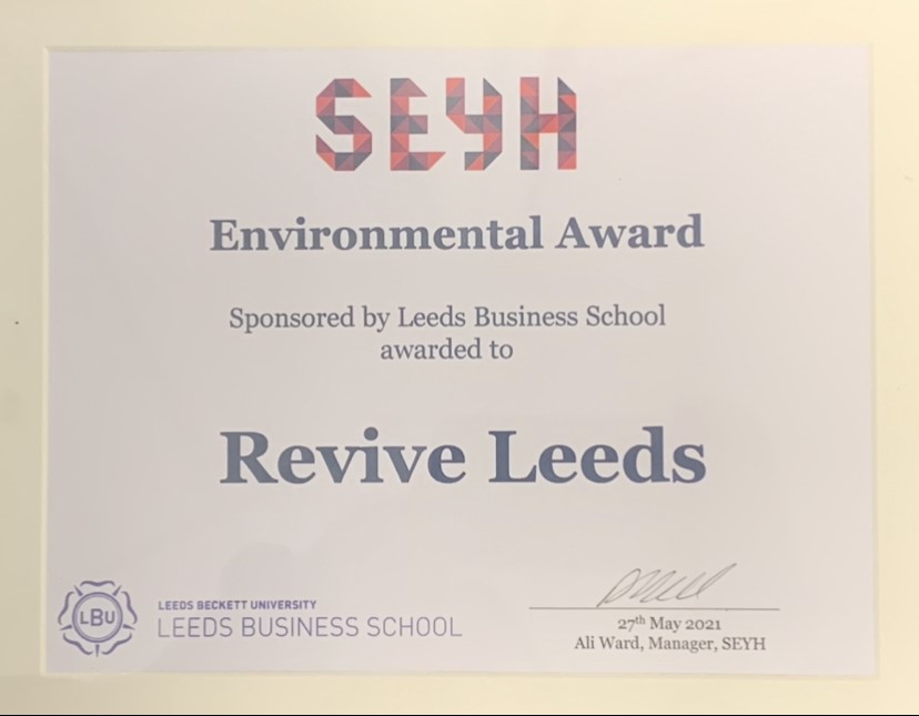A rectangle certificate that reads "SEYH, Environmental Award". The certificate is sponsored by Lees Business School and awarded to Revive Leeds. The certificate is signed: 27th May 2021 by Ali Ward the Manager at SEYH.