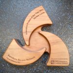 The image features a wooden triangular Innovative Project of the Year 2017 Award, presented to Revive Leeds, that reads "Furniture Re-use Network. Annual Conference 2017".