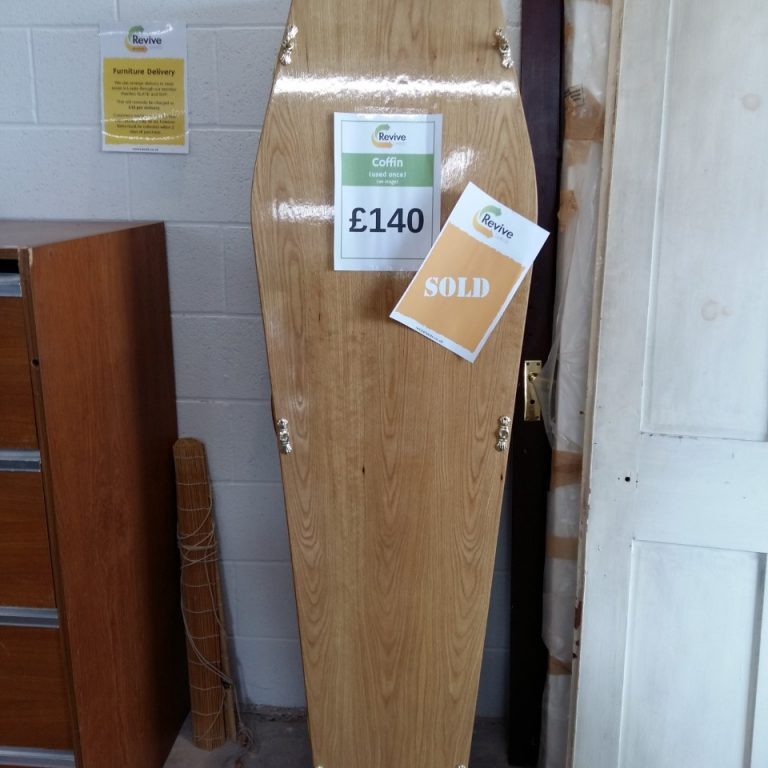 The image features a wooden coffin with a sign displayed that reads "Revive Leeds. Coffin. £140. SOLD".